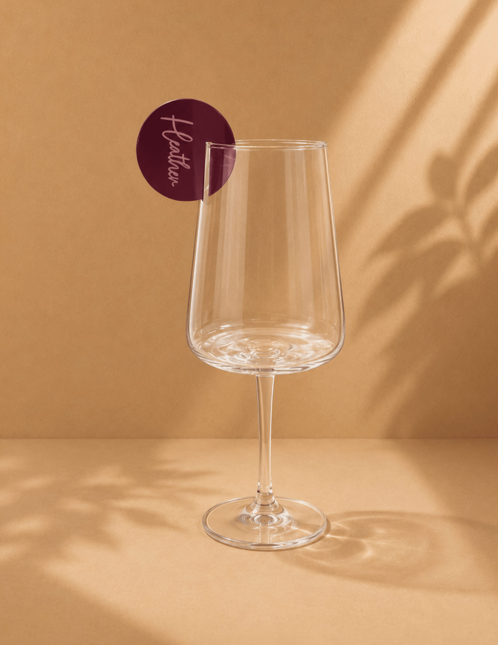 Personalized acrylic drink charm clipped to a wine glass for identifying beverages at events.