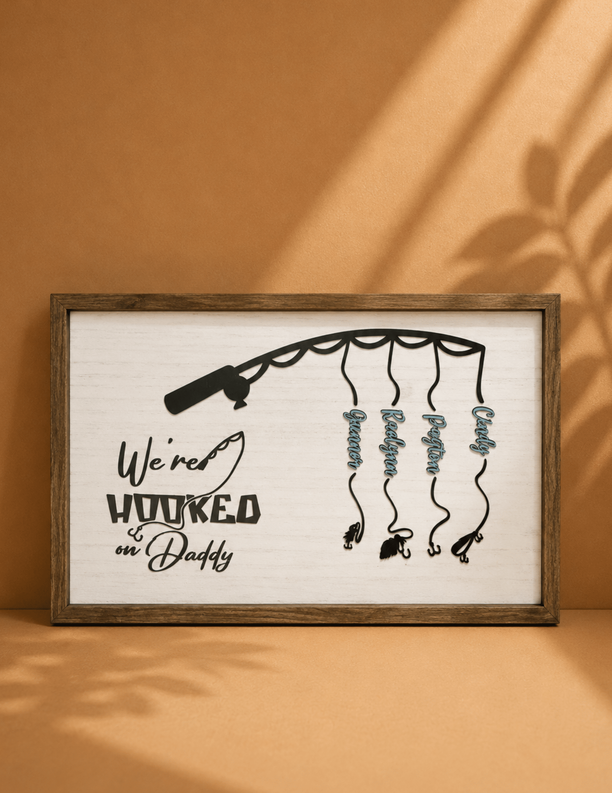 We're Hooked on Daddy personalized fishing wall décor with custom names hanging from a fishing rod.
