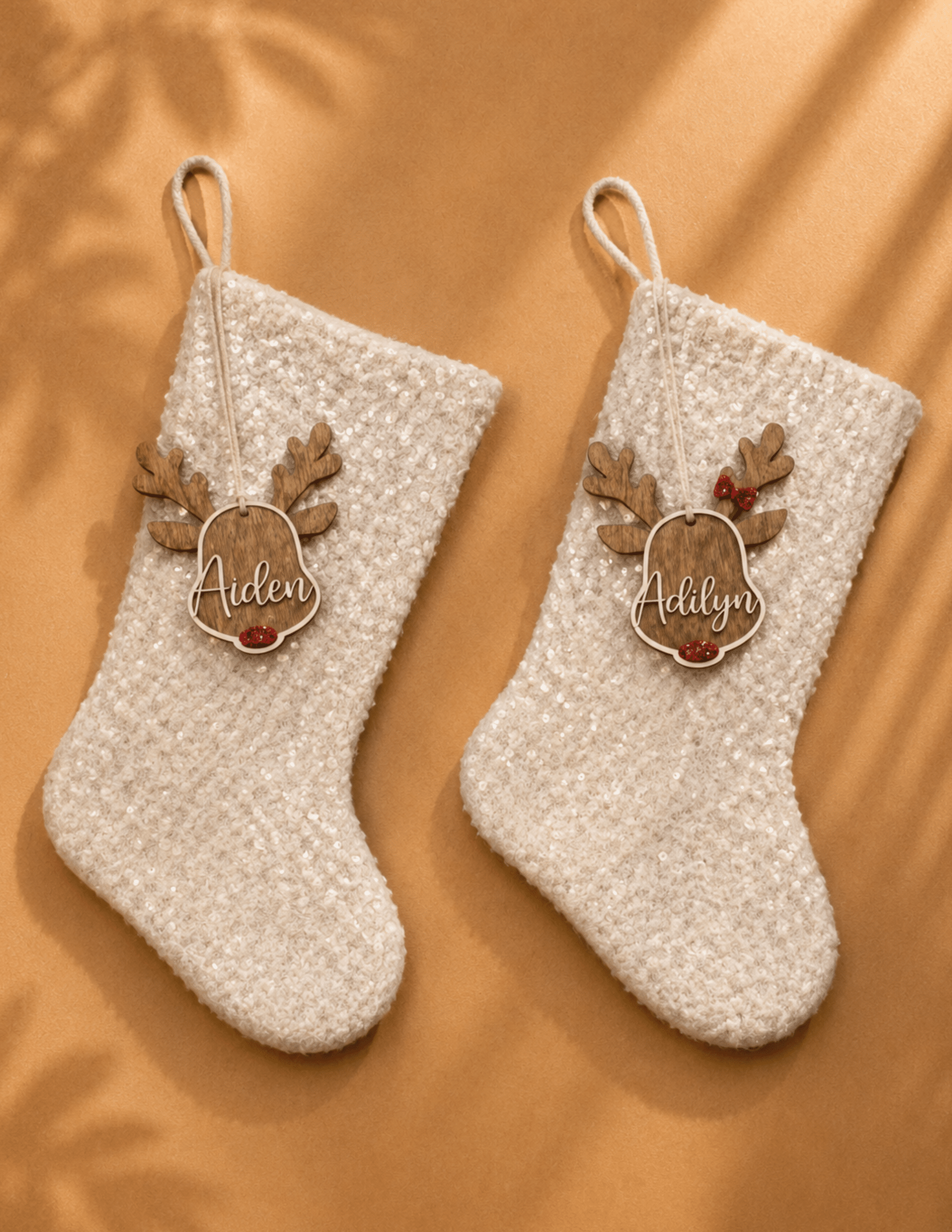 Personalized wooden reindeer stocking tags with custom engraved names hanging on white Christmas stockings.