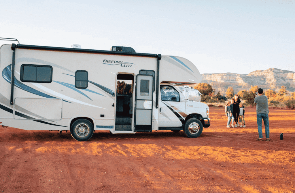 Family standing beside their RV at a scenic campsite, celebrating new adventures with gifts for new RV owners.
