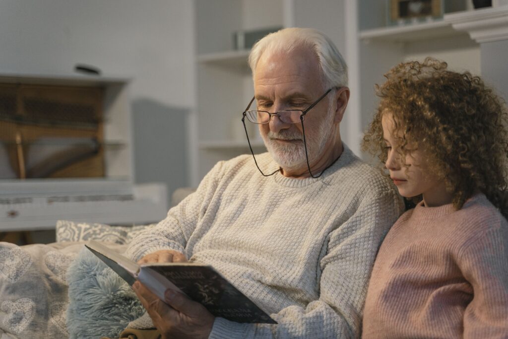 Grandfather reading a book with his granddaughter