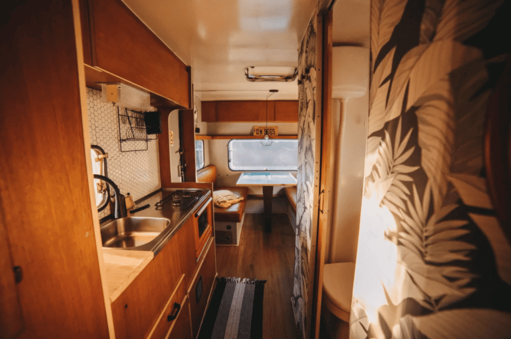 Small camper interior with warm wood finishes and cozy decor
