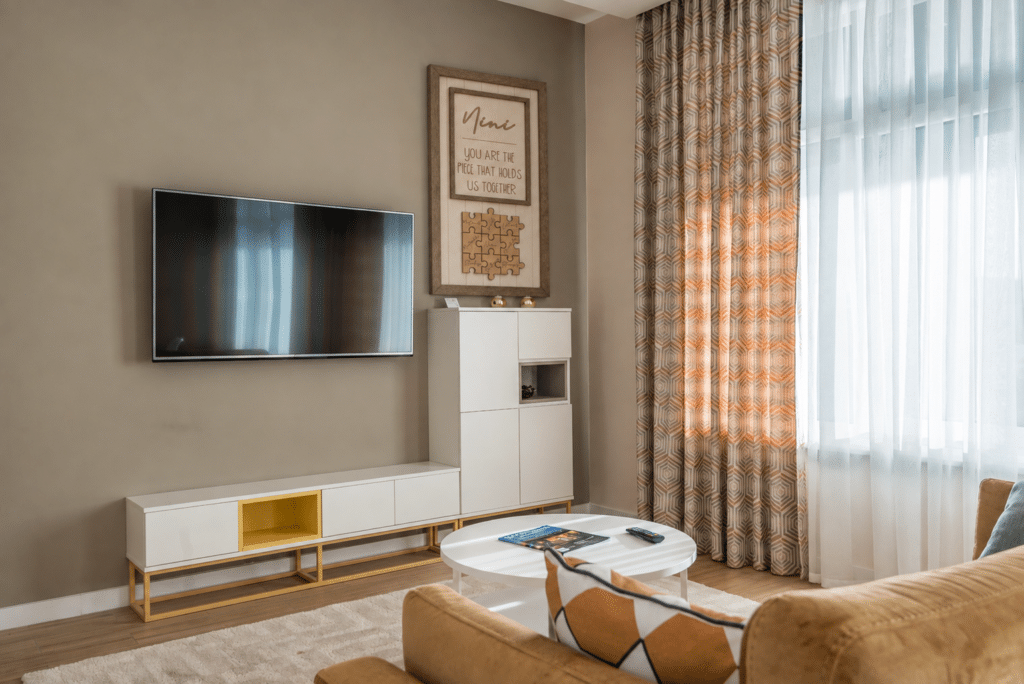 Modern living room featuring handmade home decor, including a handcrafted wooden wall sign displayed above a white cabinet, adding warmth and personality to the space.